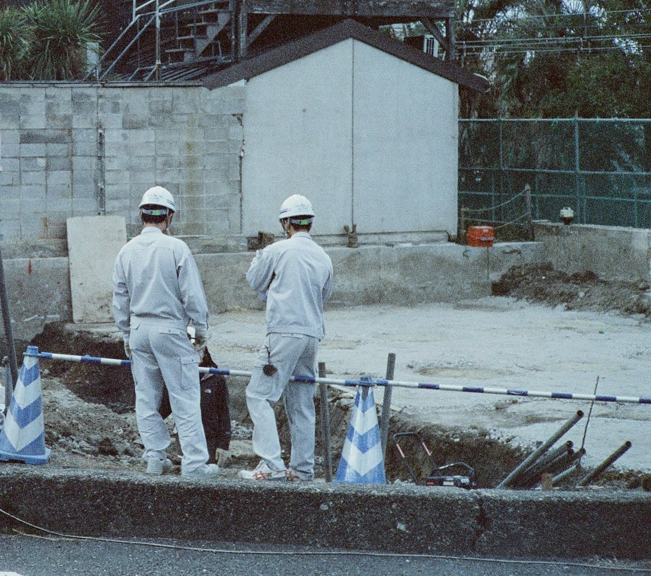 日本の工事現場でヘルメットを着けて現場を確認する二人の後ろ姿のイメージ写真